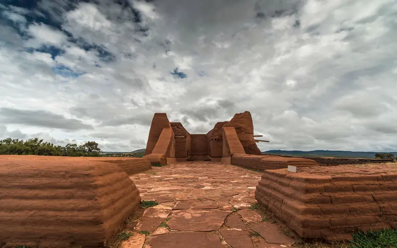 An adobe building under cloudy skies.