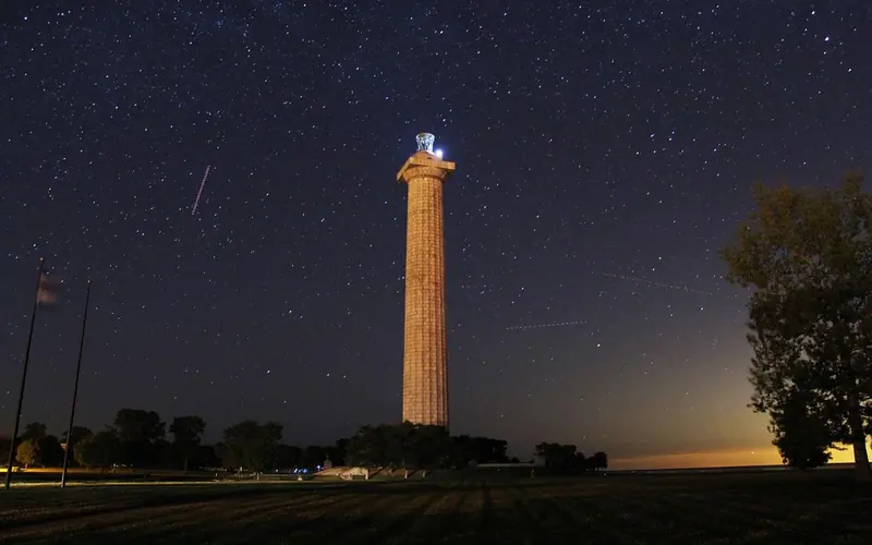 Night sky with Memorial Column in the middle with sun just starting to come up in lower right corner