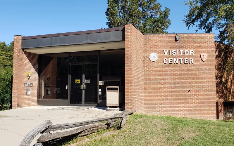Pictured is the front of the brick visitor center under a cloudless blue sky.