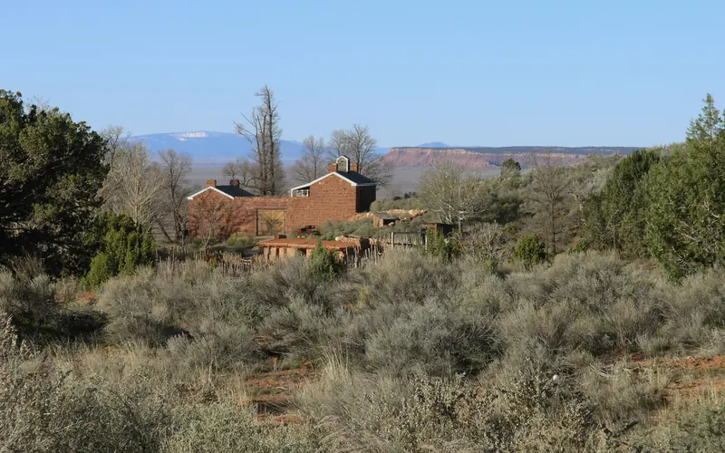 A sandstone fort rests between desert scrub in the foreground and a mountain in the distance.