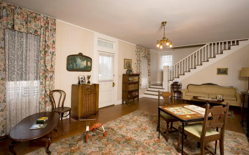 A view of the formal living room features a tricycle, table and chairs, and radio