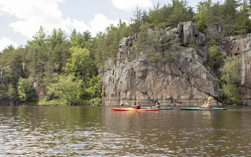 Kayakers pass impressive cliffs.