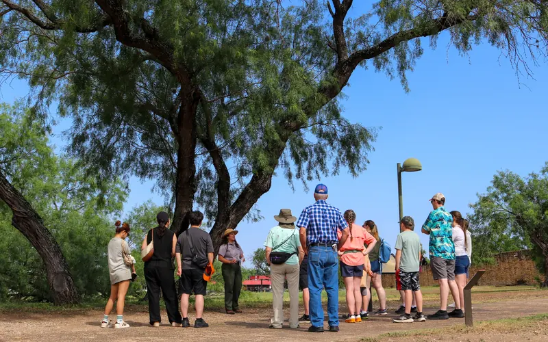 Park Ranger begins a tour through Mission San José under a large mesquite tree