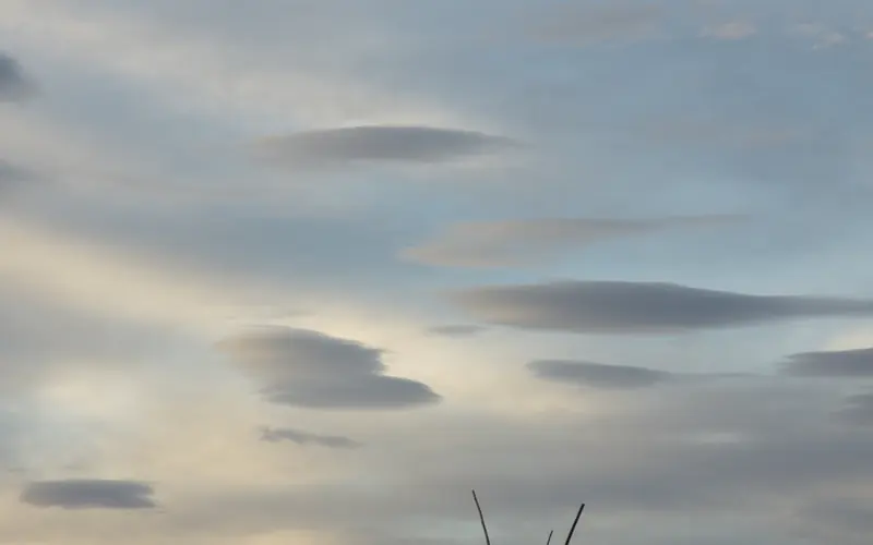 A tipi frame is silhouetted by the evening sky.