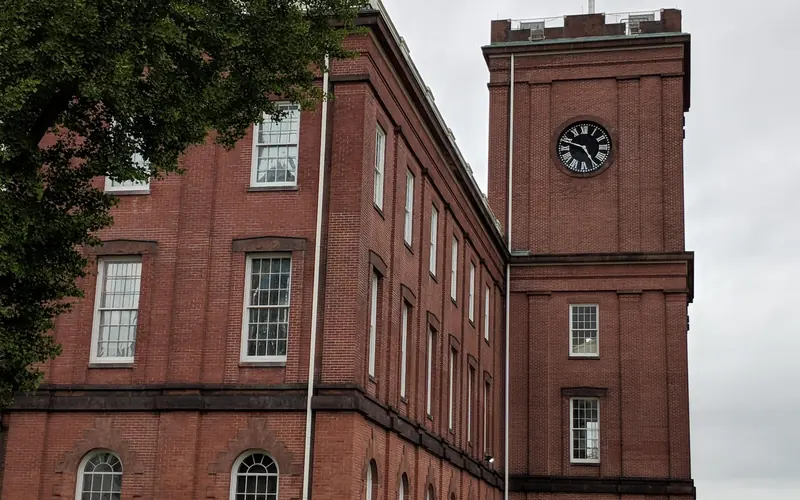 The tower of the Armory with the flag at full mast blowing in the wind on a cloudy day.