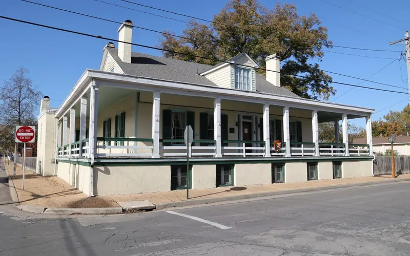 Cream colored house with a covered porch on a street corner.
