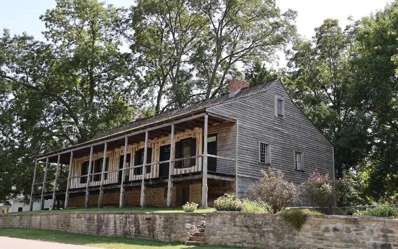 A large raised building with a covered porch and vertical log construction visible.