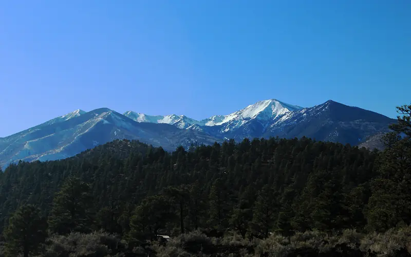 a massive volcano rising behind a smaller, tree-covered volcano in the foreground