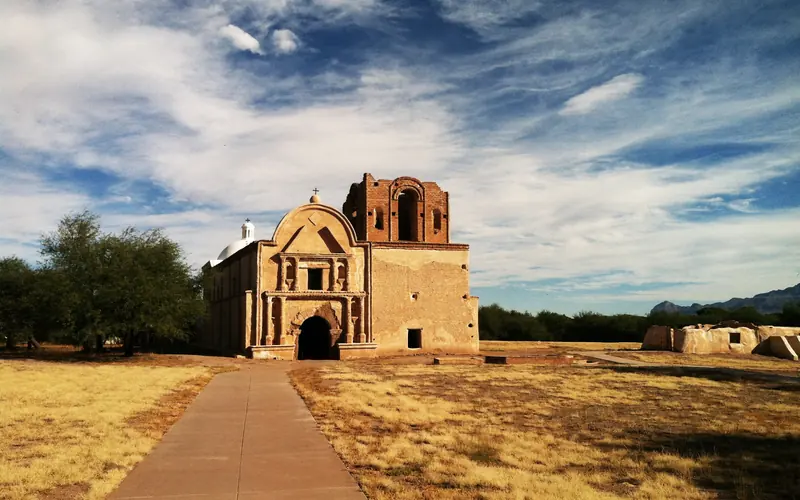 long paved sidewalk leads to adobe mission church