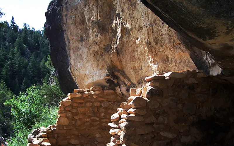 sunlight illuminates stone walls in a canyon cliff dwelling