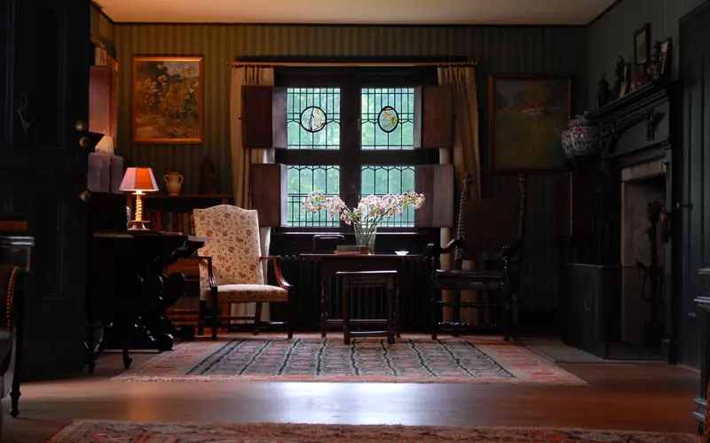 The inside of a living room with two arm chairs and a table in between.