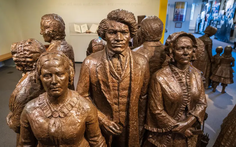A bronze statue group of people wearing 19th-century clothing.