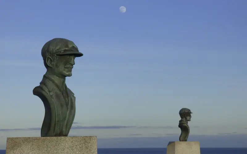 Copper busts of the two brothers with the moon visible in the blue sky.