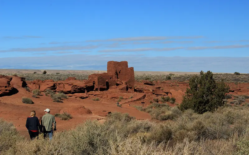 a man and woman walking toward a three-story sandstone tower
