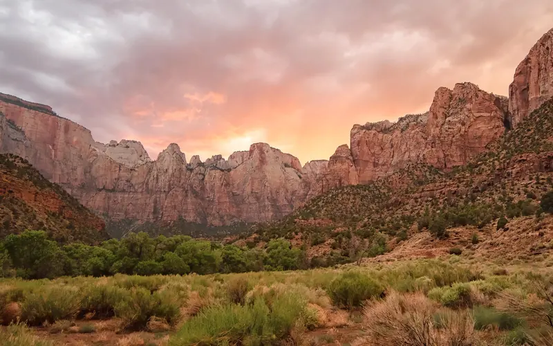 The sun sets behind large red and white towers of sandstone.